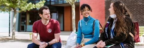 Students sitting on a bench Three students sitting on a bench chatting